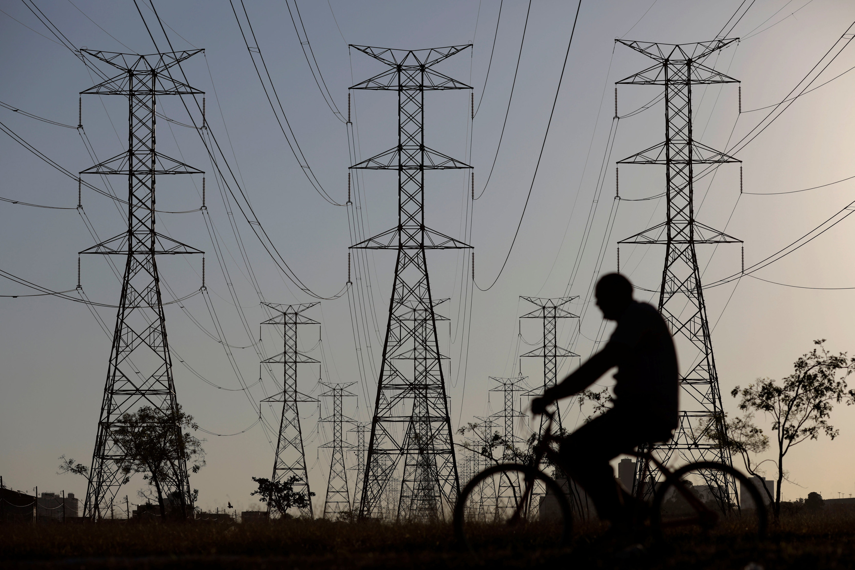 A man rides a bicycle near power lines connecting pylons of high-tension electricity, in Brasilia, Brazil  August 31, 2017. REUTERS/Ueslei Marcelino